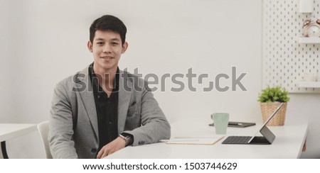 Portrait of young businessman sitting in his office room and smiling to the camera 