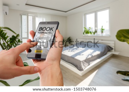 holding a smartphone with booking hotel room app on screen for make reservation