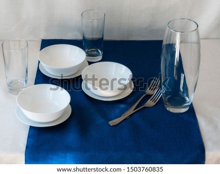 still life in Scandinavian style blue and white tablecloth, glass tall glasses, white plates