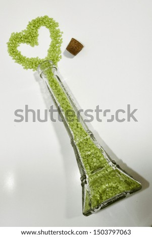 Green pellets in Eiffel Tower shaped glass bottle spilling in a love heart
