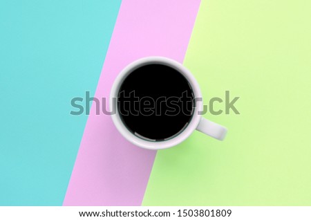 Small white coffee cup on texture background of fashion pastel pink, blue and lime colors paper