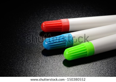 Colored felt pens on a black grained surface of the table