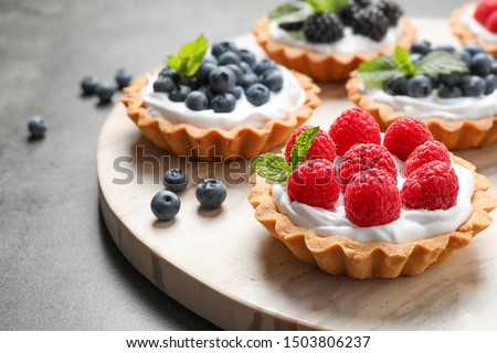 Different berry tarts on light table. Delicious pastries Royalty-Free Stock Photo #1503806237
