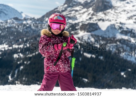 Girl in pink outfit on a ski with snow in Dolomites, Italy
