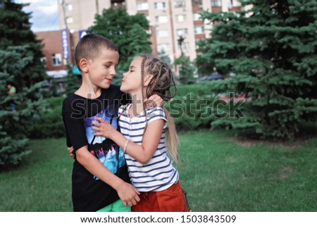 Two happy school girl and boy playing together on the green grass in the park in summer, first love feeling in childhood, true emotions, outdoor lifestyle. 