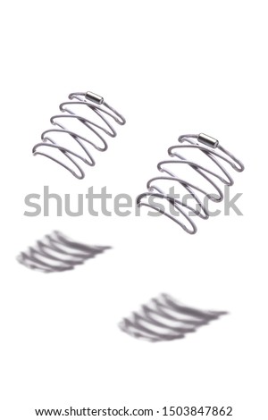 The photo of light grey shoelaces with silver tips, hanging in the air on a white background. Shoelaces is casting a shadow. 