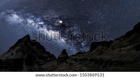 Universe space shot of nebula and milky way on hill under amazing starry blue night sky, large ravine. Silhouette of Snow Mountain Grand Canyon of U Thong Stone Mill Suphanburi, Stonehenge of Thailand Royalty-Free Stock Photo #1503869531