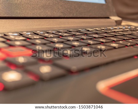 Black keyboard with red backlight,  partly blurred keyboard