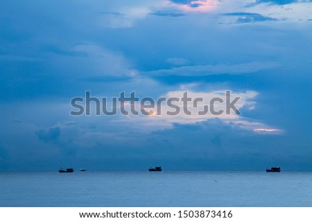 Sea horizontal background at morning blue hour in Dong Hoi, Quang Binh. Some small fishing ships coming back after a night trip are also involved.