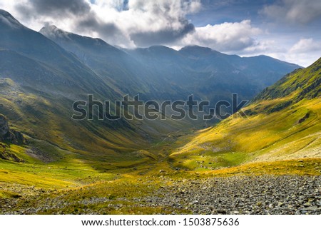 Mountain landscape with clouds and sun passing through them. Fagaras Mountains, Romania