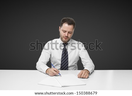 businessman writing on paper sitting at table