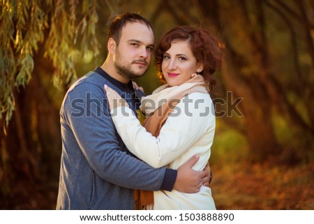lovers man and woman 30 years old autumn in the park hugging and looking at the frame