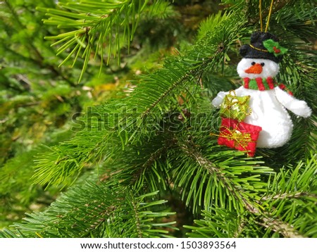 Christmas felt decoration on a spruce branch. Handmade bauble figurines of snowman. Holiday background with a copy space.