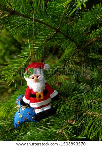 Christmas felt decoration on a spruce branch. Handmade bauble figurines of Santa Clause. Holiday background with a copy space.