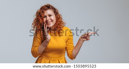 The red-haired girl points at the light gray background. Copy space. Banner panoramas