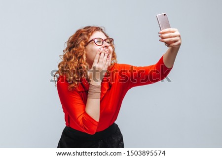 girl takes a selfie on the phone on a light gray background