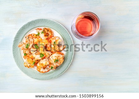 Cooked shrimps, shot from the top on a rustic wooden background with a glass of rose wine and a place for text