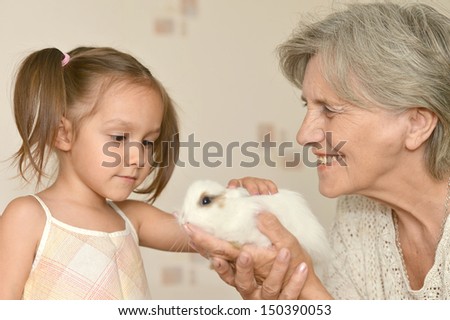 Happy elderly woman and a young girl with a small rabbit