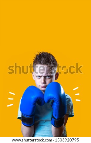 Severe boy in blue Boxing gloves on a bright yellow background