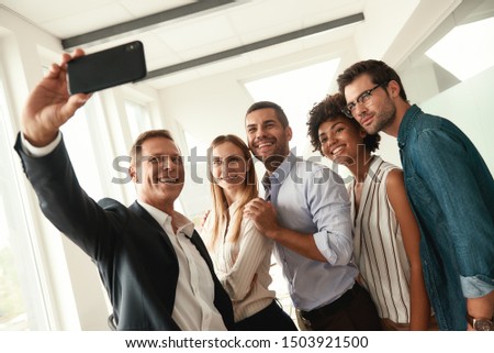 Happy team Group of smiling colleagues taking selfie while standing in the modern office