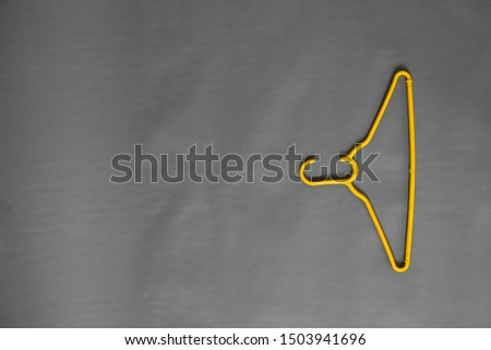 a yellow hanger lies among ordinary hangers