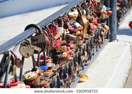 A large number  of wedding padlocks on a cast iron fence. Closeup. Selective focus. Accent for the middle of the frame. Conceptual photo. Background.

