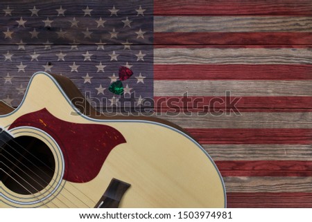 Acoustic guitar placed on an old wooden table, With a picture of an American flag on wood, Close-up