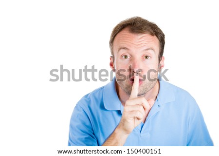 Closeup portrait of guy with blue shirt placing fingers on lips as if to say shhh, isolated on white background with copy space