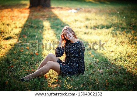 a girl in a black floral dress on the grass, shot on a Sunny and warm September day against the sun