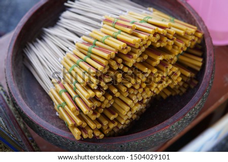 Buddles of candles and joss sticks in a tray in a Thai temple. This's for Buddhist praying