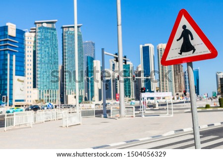 in the foreground a sign of pedestrian crossing on the background of skyscrapers in Qatar