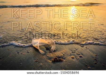 Plastic glass lies on the beach in sunset and pollutes the sea and marine life. Garbage rubbish trash problem environmental pollution. Keep the sea, plastic free. Concept of pollution control.