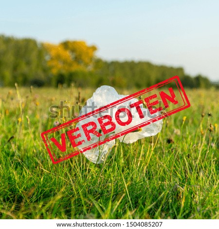 Plastic ban in Germany. Used plastic bag dumped on the green grass. Red stamp over the bag with word Banned, Verboten. Environmental pollution concept. Verboten - banned, forbidden