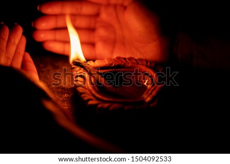 Hand holding or protecting diya or oil lamp, lantern during Diwali celebration. Background picture for Indian Hindu festival Diwali.