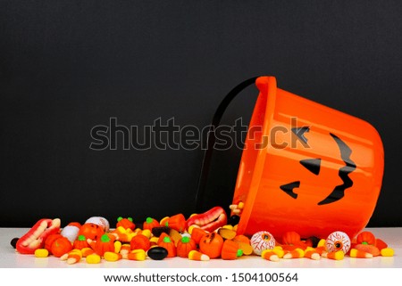 Halloween Jack o Lantern bucket with spilling candy, side view on a black background