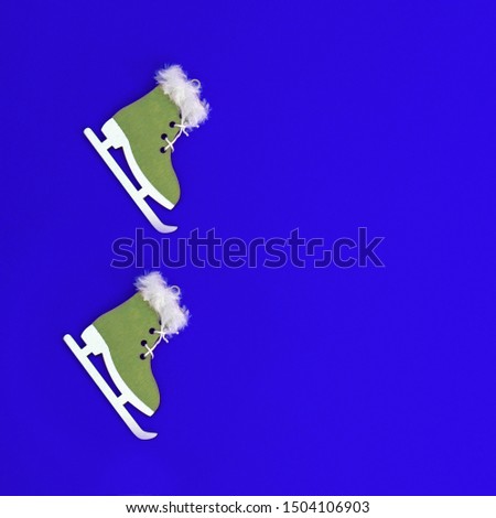 Small wooden christmas toy Green mittens on blue paper background with copy space. Flat lay minimal christmas composition. 
