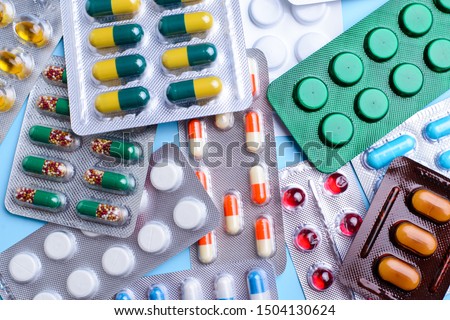Different tablets, pills in foil blister packs, medications drugs on blue background Royalty-Free Stock Photo #1504130624