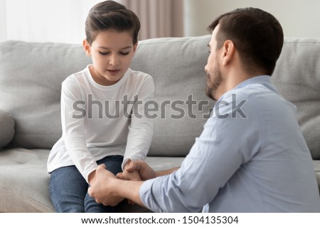 Worried loving young single father holding hand talking comforting upset little kid son sharing helping with problem, caring dad foster parent give support apologizing supporting listening child boy Royalty-Free Stock Photo #1504135304