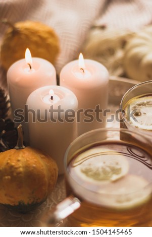 autumn cosy tea on tray with pumpkin, candles and blanket