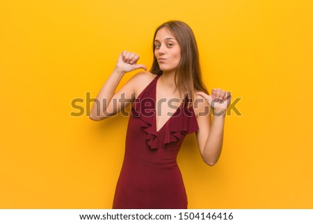Young elegant woman wearing a dress pointing fingers, example to follow