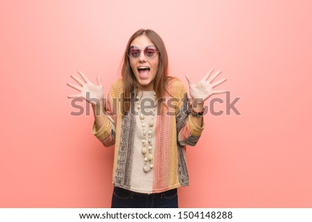 Young hippie woman on pink background celebrating a victory or success