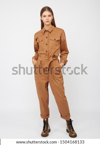 Girl in camel color jumpsuit on white backround. Royalty-Free Stock Photo #1504168133