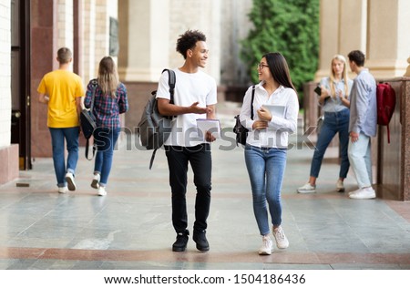 Diverse classmates chatting, walking after classes in university campus outdoors Royalty-Free Stock Photo #1504186436