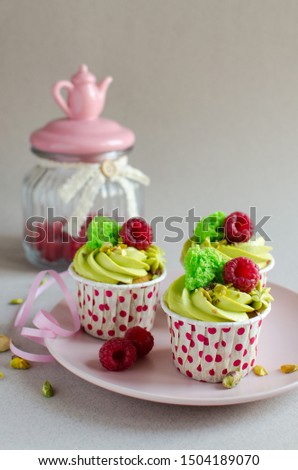 Set of pistachio cupcakes decorated with fresh raspberries on neutral color background