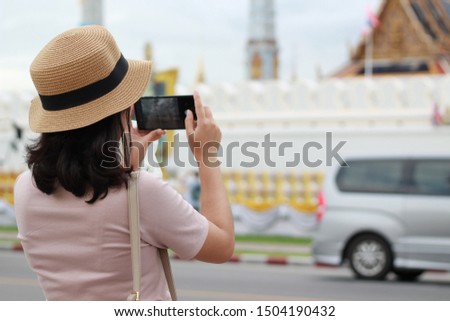 Asian woman tourists posing for pictures of tourist attractions in Bangkok At Phra Kaew Temple