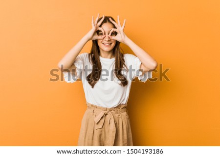 Young caucasian woman showing okay sign over eyes