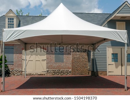 White event tent canopy erected on brick patio.