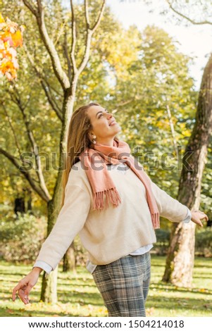 Beautiful autumn woman holding yellow maple leaf outdoors. Romantic girl and spirit autumn in fall park