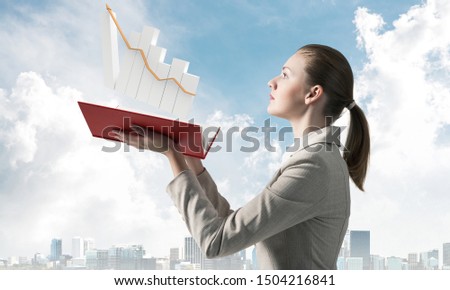 Businesswoman with growing financial graph above opened notebook. Business statistics and analytics. Stock trading and investment. Elegant young woman in white business suit on background of blue sky.