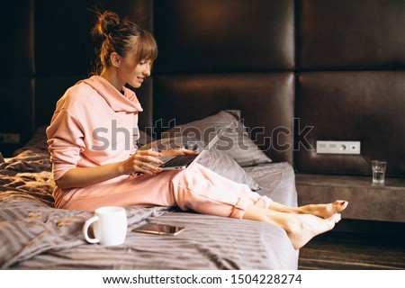 Woman in pygama working on laptop in bed